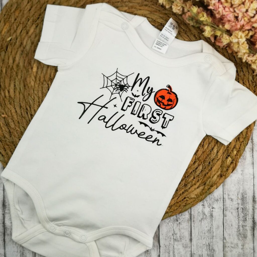 Personalisierter Babybody aus Baumwolle von Maggie Made als liebevolles Geschenk zur Geburt, flach dekoriert auf einer hellen Decke