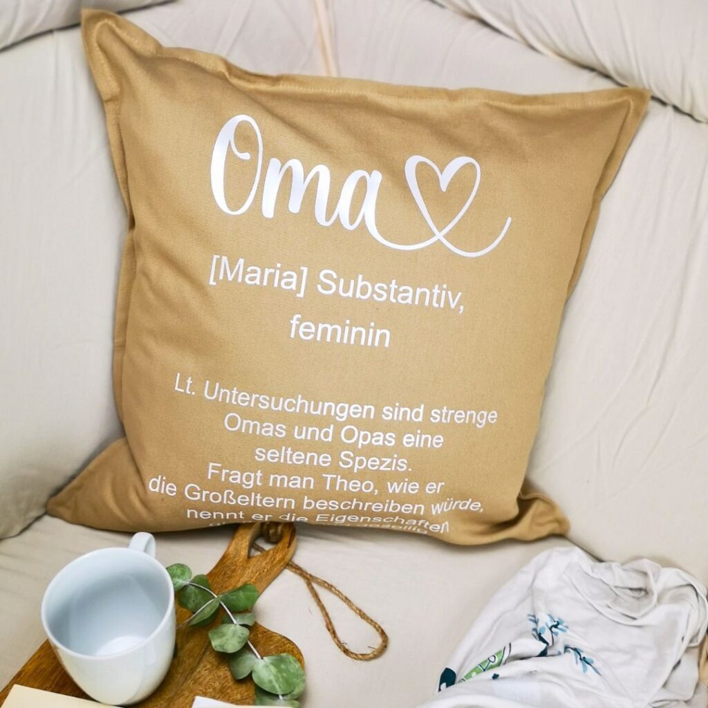 Personalisiertes Kissen für die Oma mit Definitionstext von Maggie Made, hell und freundlich dekoriert mit Lavendel auf einem Holztisch als Geschenkidee.